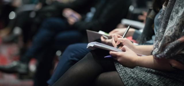 selective focus photography of people sitting on chairs while writing on notebooks by The Climate Reality Project courtesy of Unsplash.